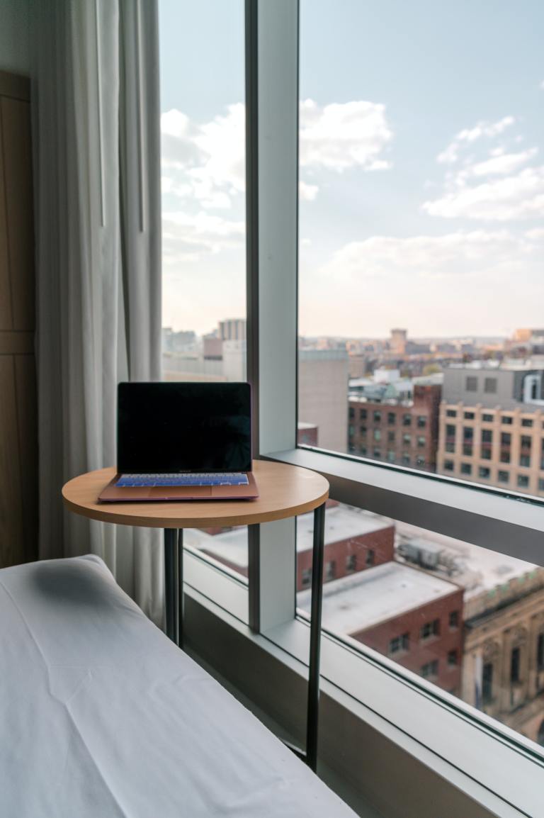 Picture of a computer sitting on a side table next to an open window