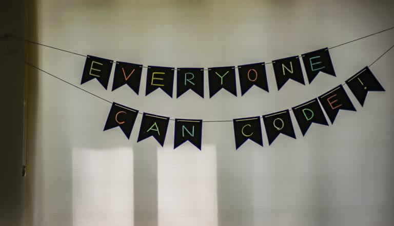 Banner of black bunting against a white wall, with the bunting spelling out "Everyone can code!"