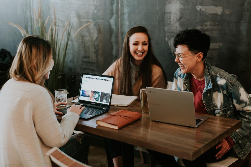 Three people working at a table on laptops