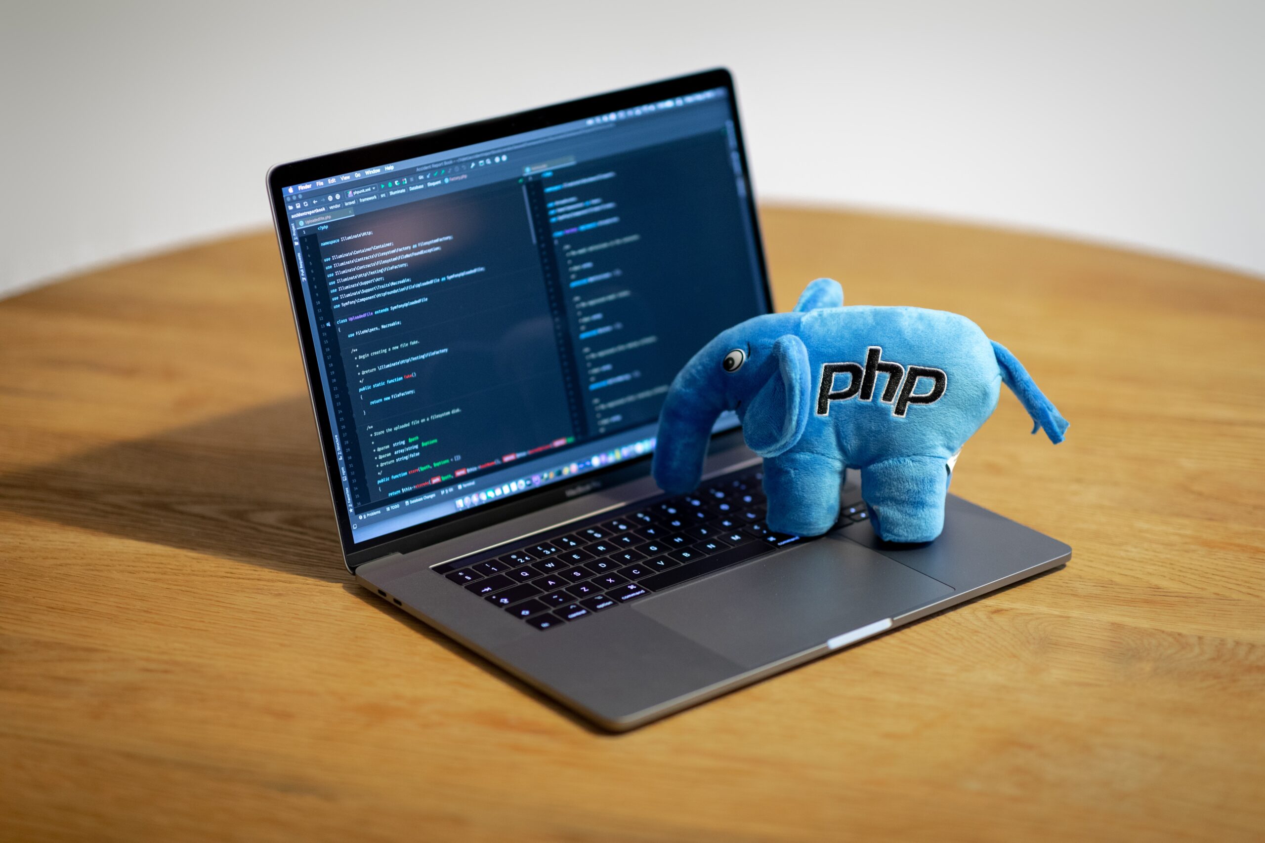 Hire dedicated PHP developers | Picture of an open laptop with a stuffed elephant with the letters “PHP” stitched into it sitting on the keyboard.