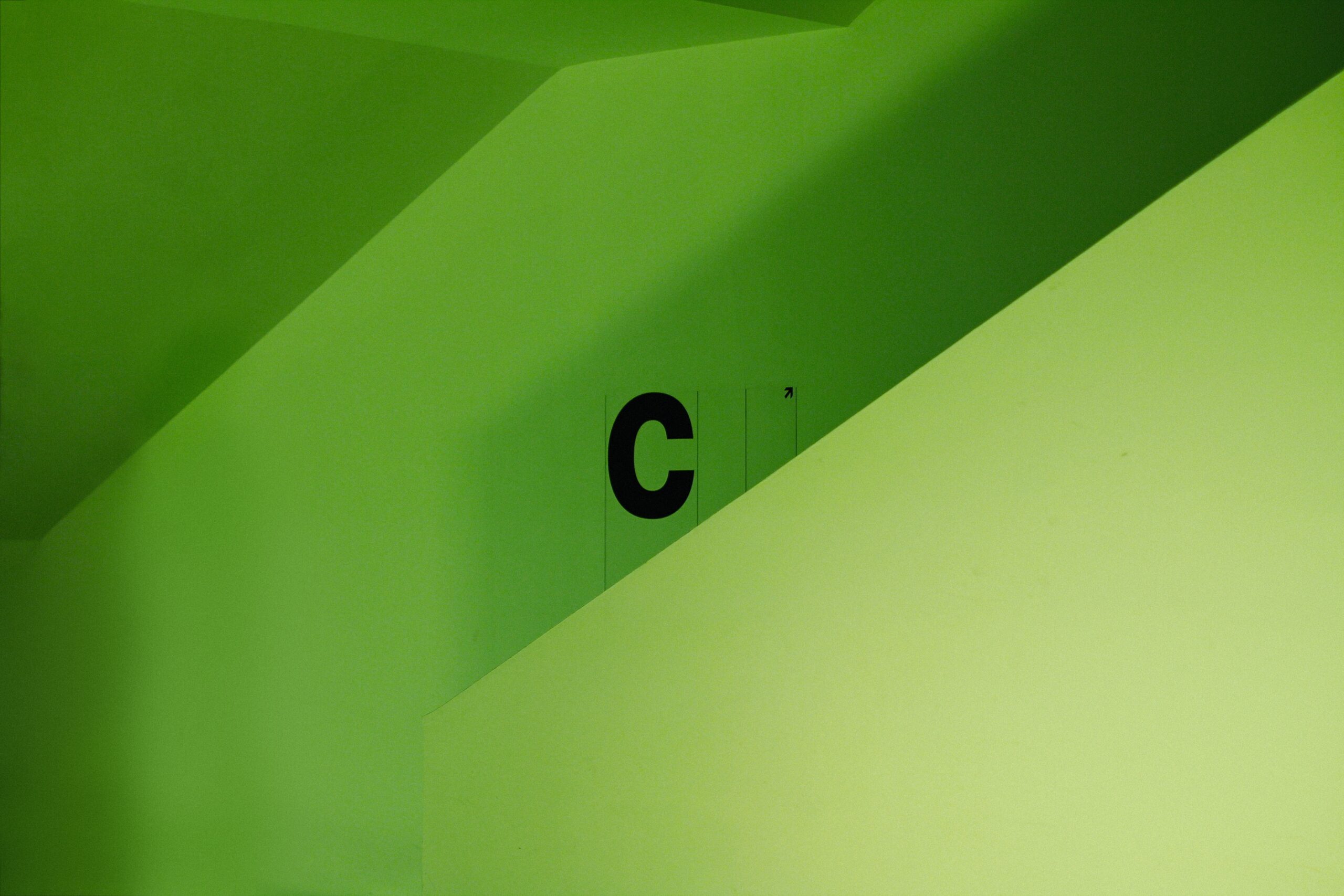 Hire C Sharp developers | Picture of the letter C in the center of the image, with multiple shades of green surrounding the letter in an angular pattern.