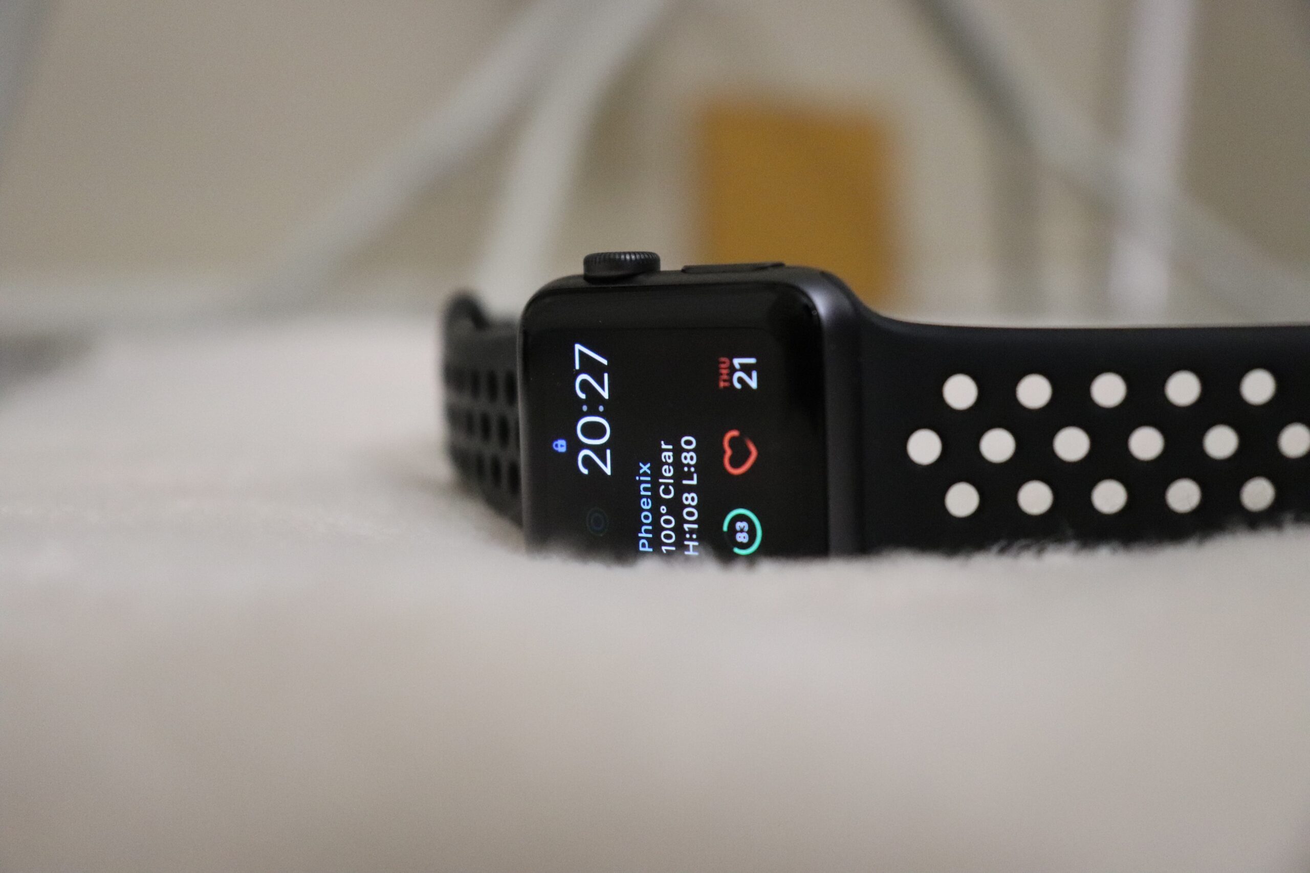 HealthTech developers for hire | Picture of a smart watch sitting on its side on a blurred, but fuzzy-looking fabric. The band to the watch is black and has perforated holes on it.