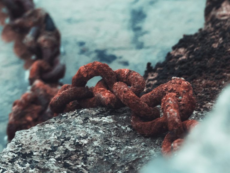 Best sites to hire Rust developers | A red rusted chain draped over a blueish pipe that's also rusted.