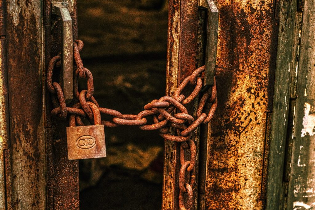 Rust developer job description template | Picture of two doors locked together by a rusty chain and padlock.
