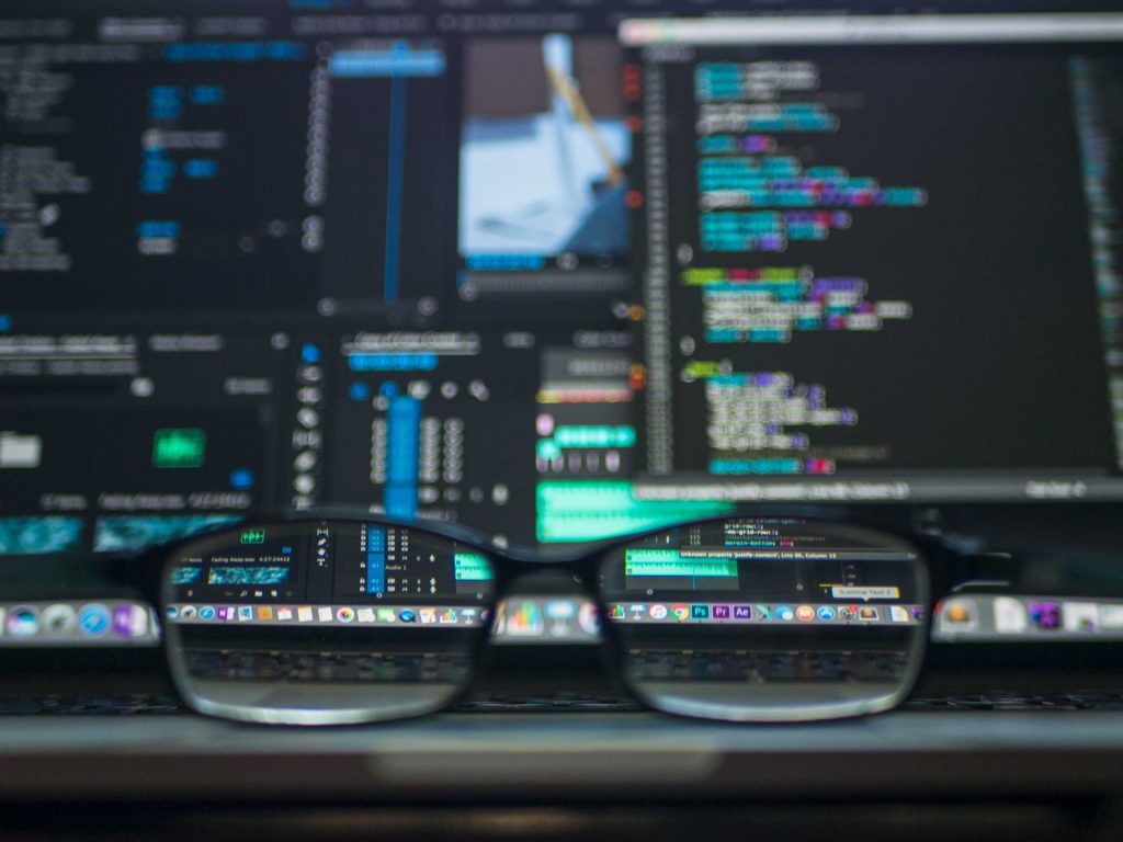 Junior SQL job developer job description | A set of eyeglasses is sitting on the keyboard portion of a laptop which is displaying distorted code.