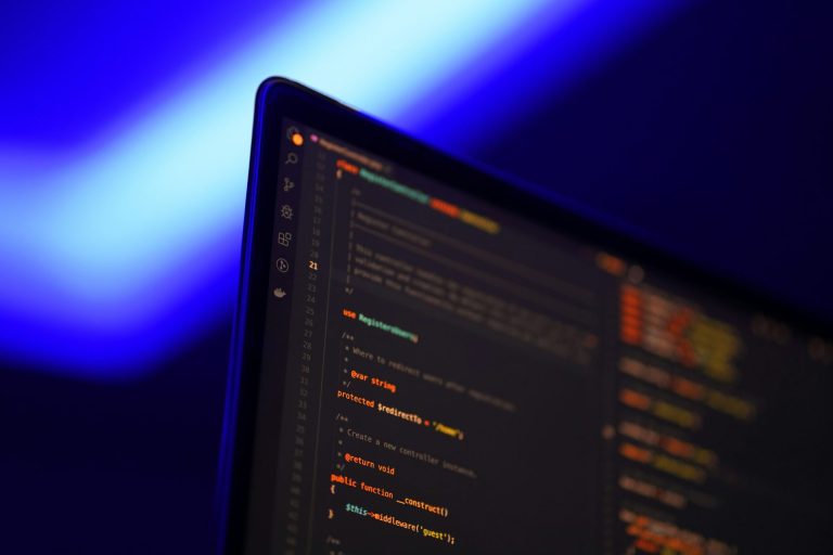 Hire dedicated Laravel developers | Blue light in the background in the upper left corner with a computer screen in the foreground that has code on it.