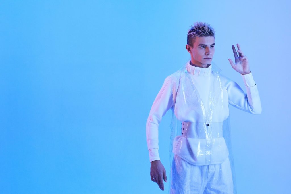 Photo of a person in a white futuristic outfit, posing robotically.